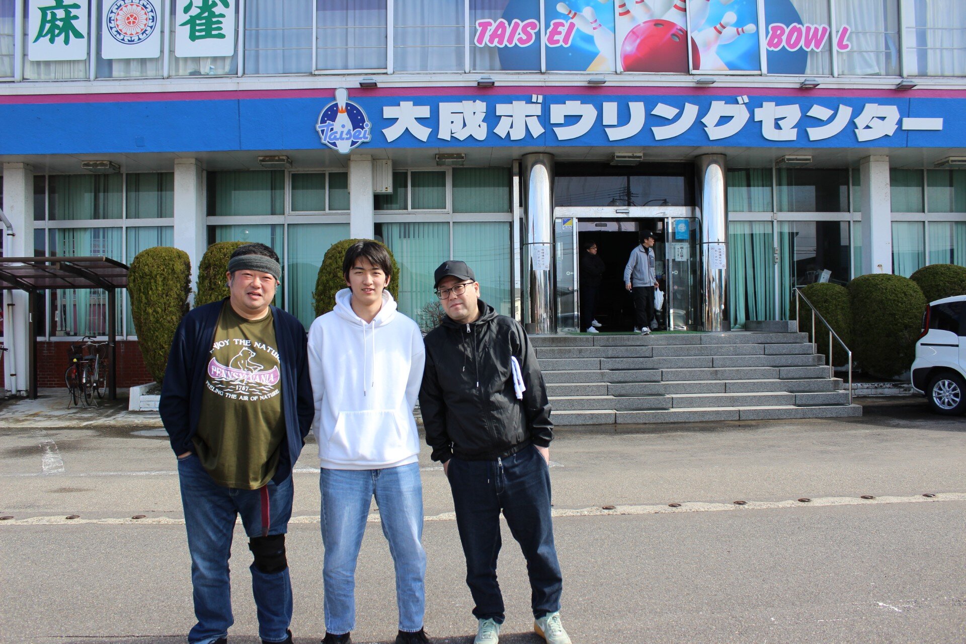 ボウリング場の前に立つ3人