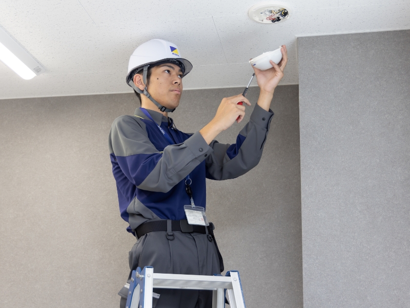 ALSOKの職員が火災報知器を点検している写真