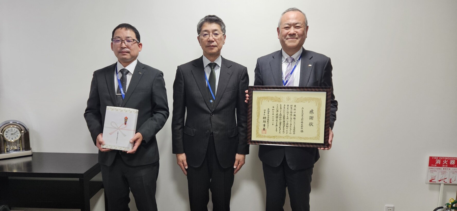 感謝状をいただき記念撮影する男性3名